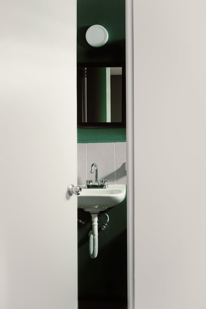 Contemporary bathroom interior with a partially open door, revealing a sleek and modern sink design.