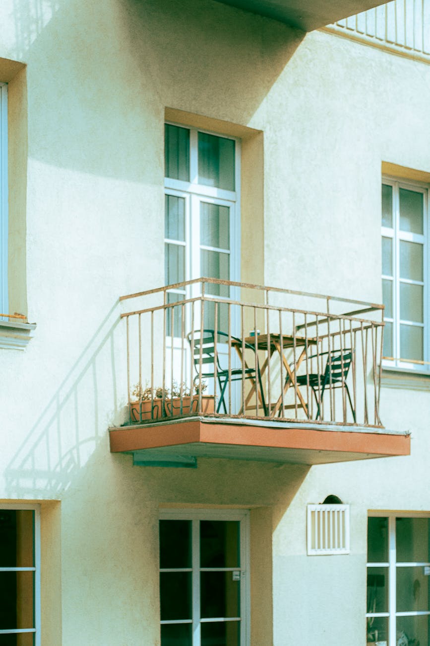 Charming urban balcony with modern chairs and table set up for relaxation.