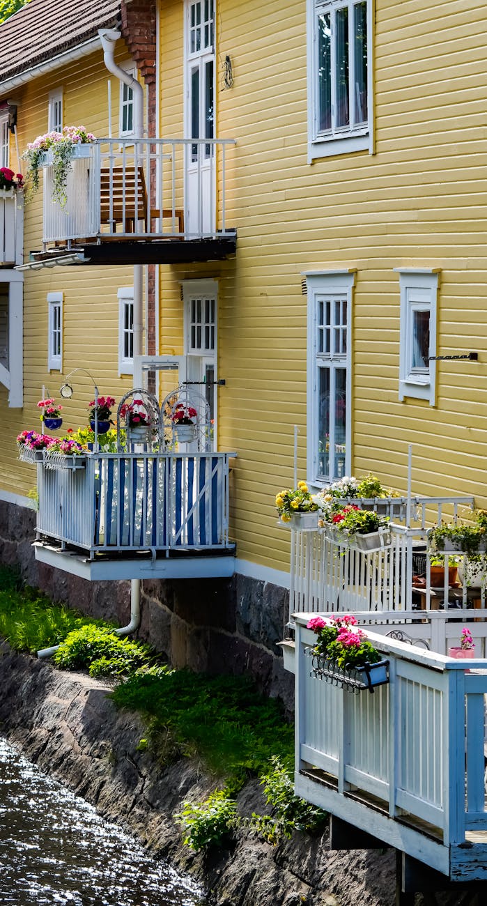 Picturesque yellow house exterior with colorful flowered balconies by the canal.