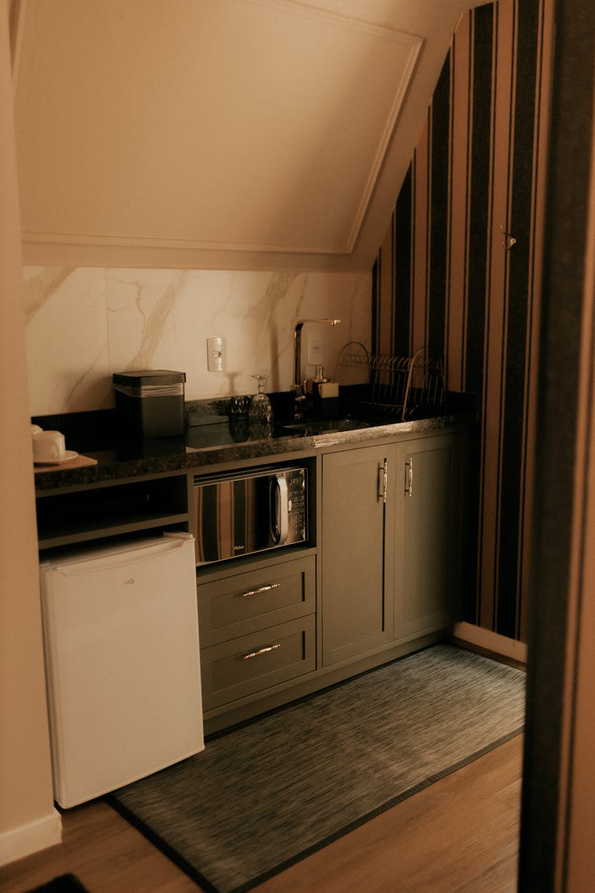 A warm, modern mini kitchen with coffee maker and microwave.
