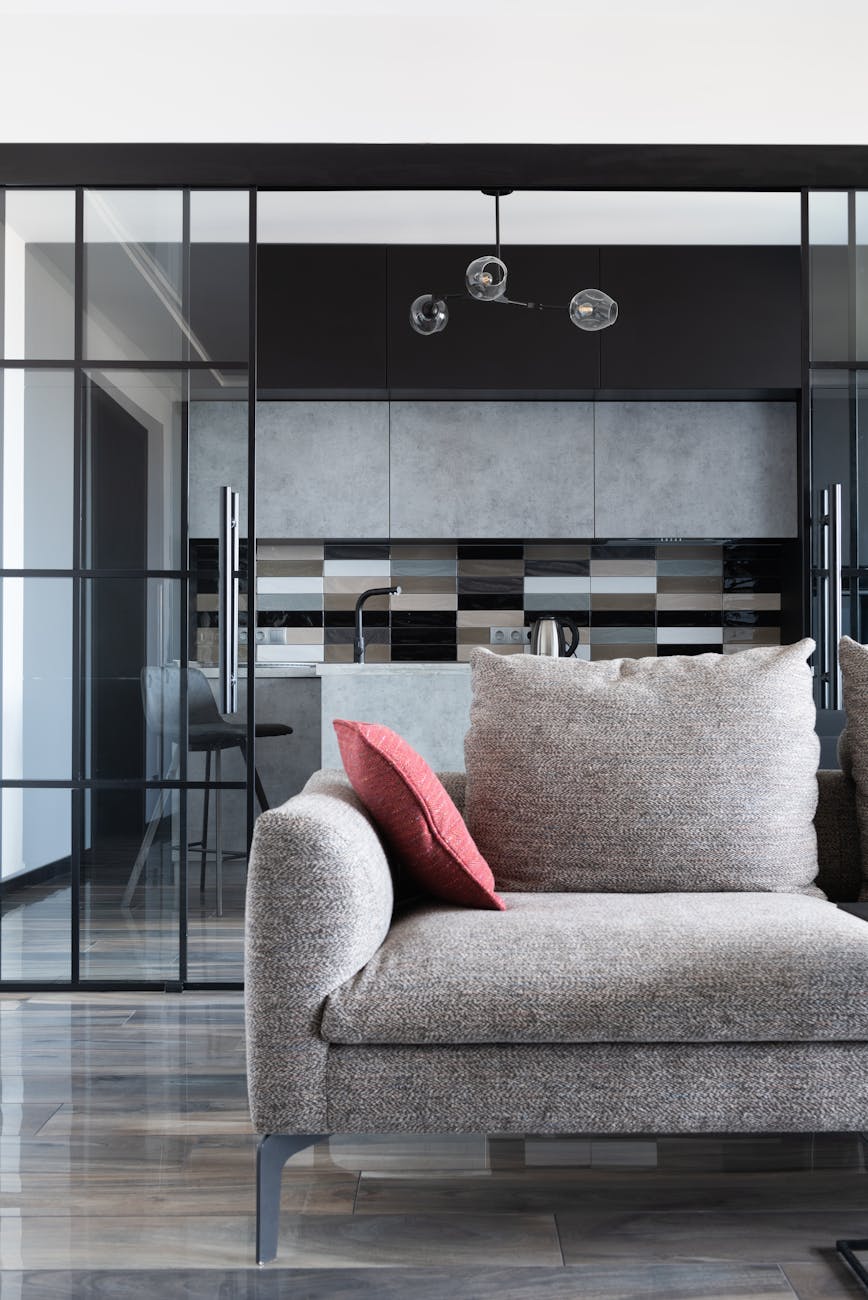 Contemporary living room setup featuring a sleek sofa with a stylish kitchen view in the background.
