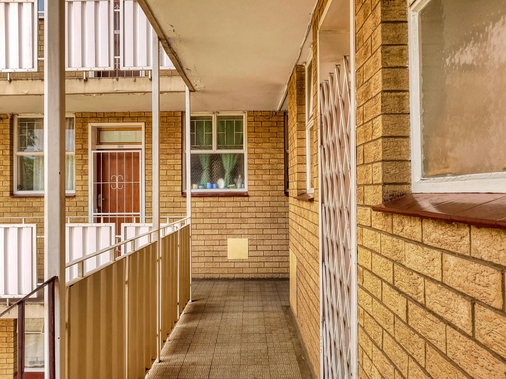 Warm and inviting apartment corridor with brick walls and doorways, exuding a cozy architectural charm.