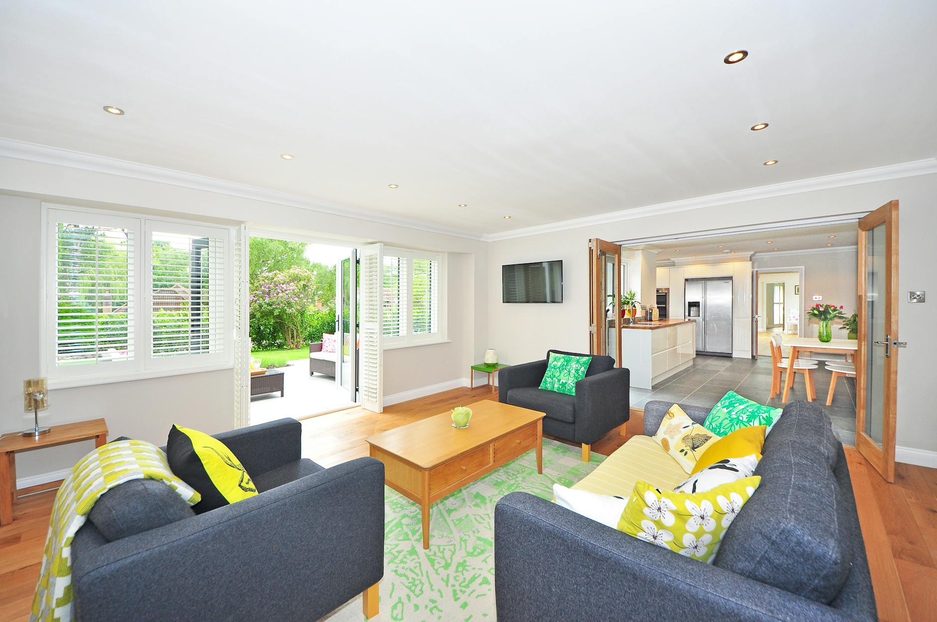 Modern living room with open plan kitchen and garden view, bright and airy ambiance.