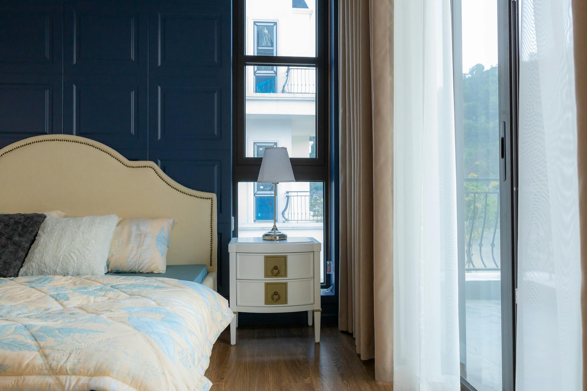 Brightly lit modern bedroom with elegant decor and a view through large windows.