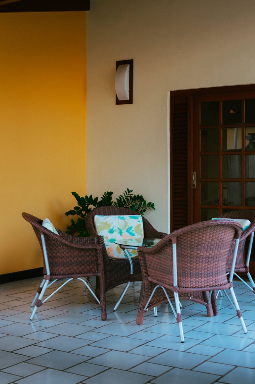Inviting patio setup featuring wicker chairs around a table against a bright yellow wall.