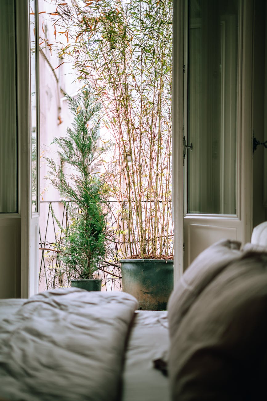 A tranquil bedroom scene featuring an open balcony with lush potted plants, inviting relaxation.